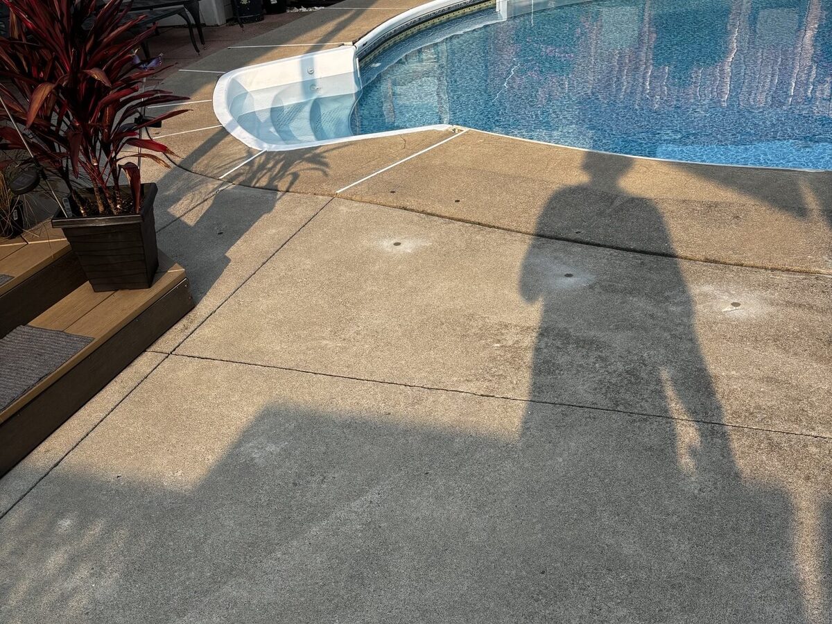 Stoney Creek concrete pool deck beside an in-ground pool after polyurethane concrete lifting, with patched injection holes