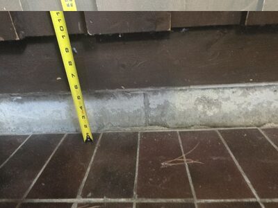 Settled commercial laundry room tile floor dropped nearly 6 inches below the wall trim in Lindsay, Ontario before concrete leveling