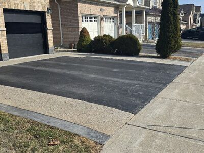 Settled exposed aggregate concrete driveway around an asphalt centre in Maple, Ontario before polyurethane concrete leveling