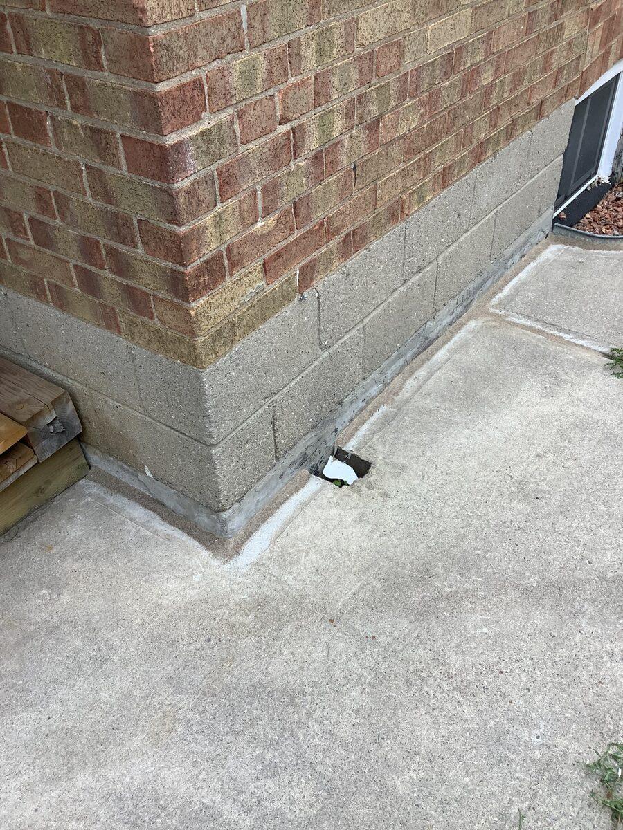 Close-up of perimeter sealant where the driveway meets the home's brick foundation