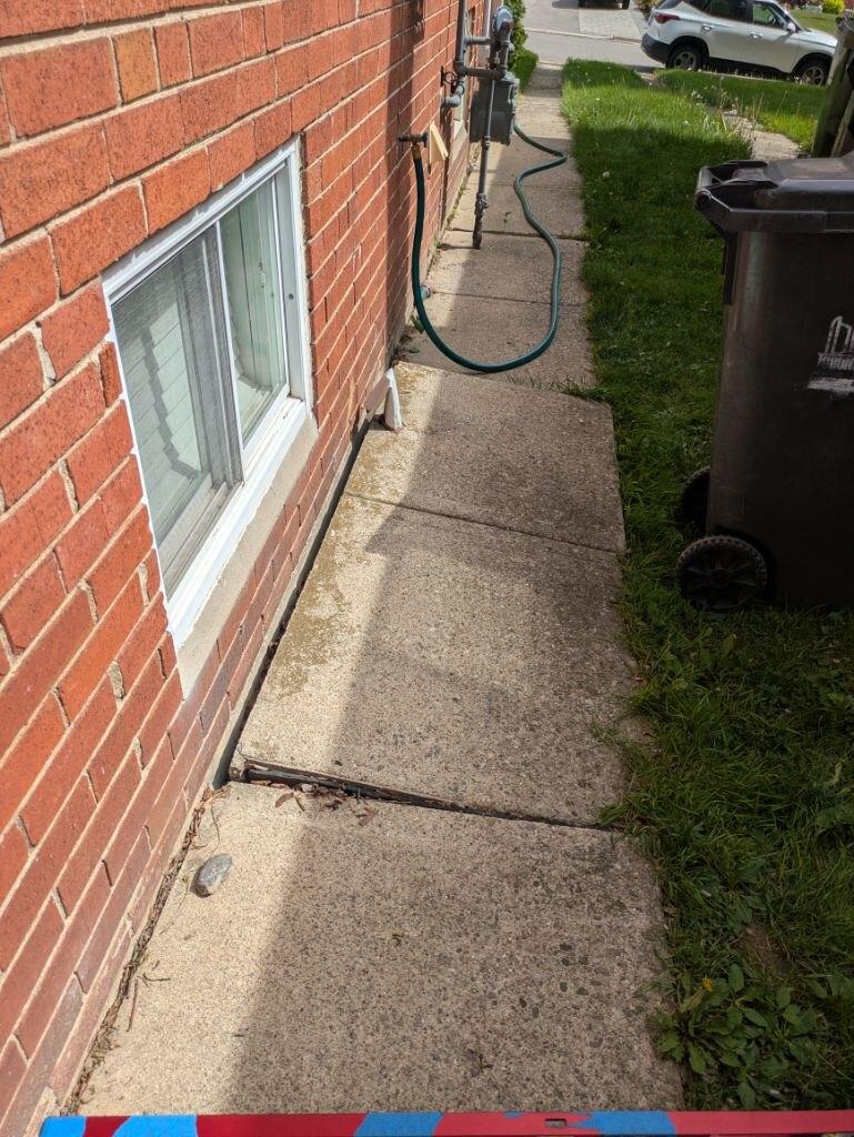 Severely settled concrete walkway beside a North York home before repair